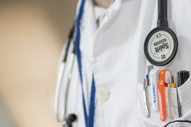 A close up of a doctor wearing a white coat, with a stethoscope around his neck.