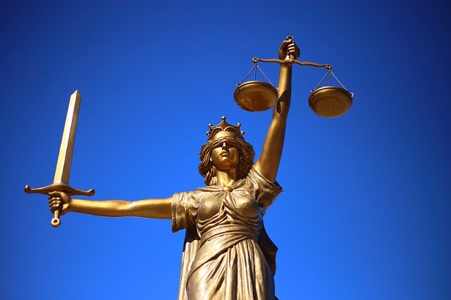 A golden statue of lady justice, holding up a sword and a set of scales