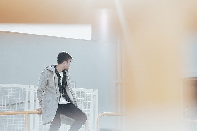 A teen boy sitting on a stair railing and looking away from the camera. Teens lives can be devastated by sex crime accusations.